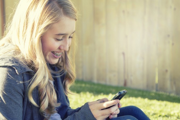 Teenage girl smiling while using a cell phone