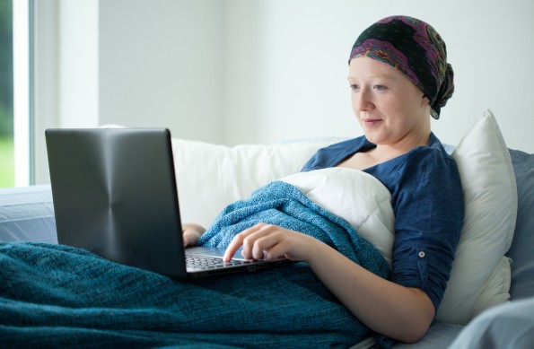 Smiling cancer girl using laptop