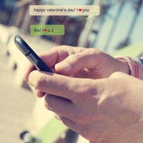 a young man sending a text message with a smartphone with the text Happy valentines day, I love you