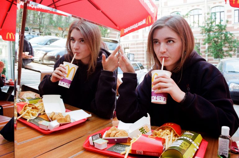 Foto van een meisje die fast food eet voor een spiegel.