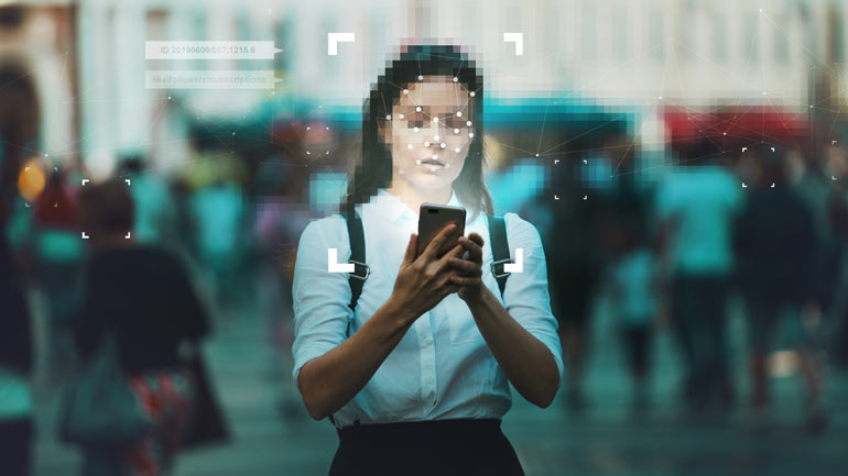 Vrouw met gezichtsherkenning en smartphone in haar hand.