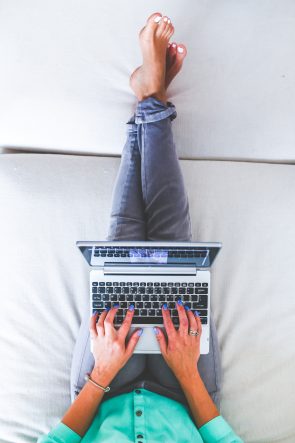 Vrouw werkt thuis met laptop op bed.