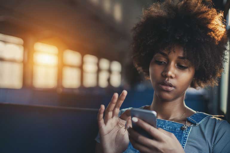 Vrouw kijkt in trein video op mobiele telefoon.