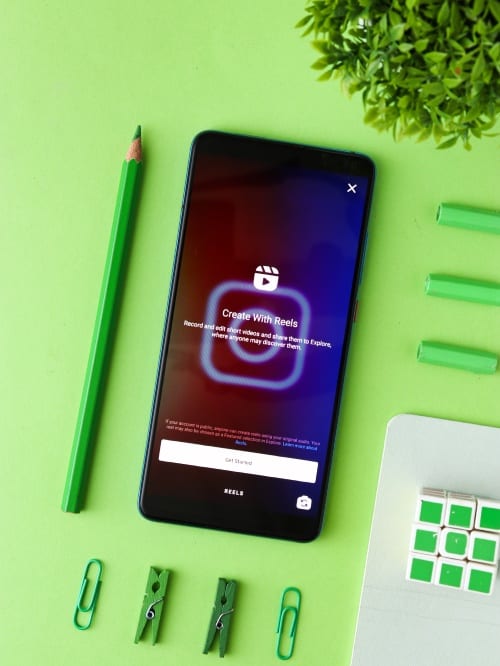 Smarphone met Instagram Reels op groene achtergrond