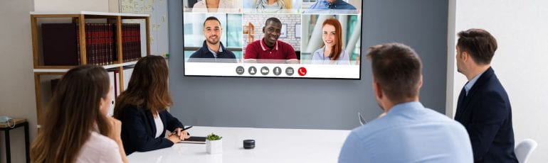 Vergaderen op kantoor met mensen op afstand in videocall op scherm