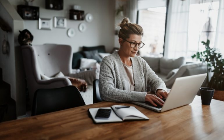 Vrouw werkt vanuit huis achter laptop bij artikel hybride werken en digital employee experience