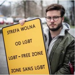 Man die bord vasthoudt met daarop in verschillende talen 'LGBT-free zone'